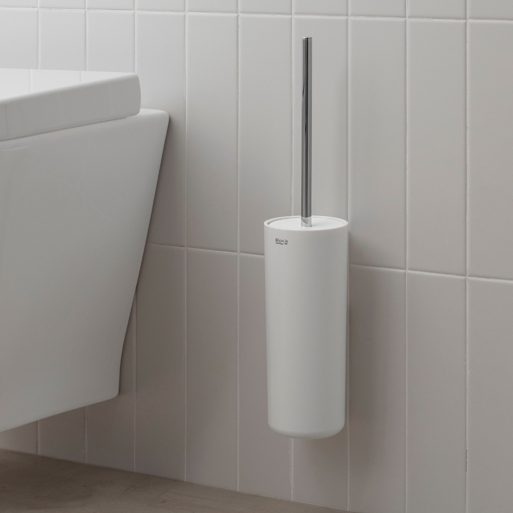 Lifestyle image of the Roca Sonata Chrome Wall-Mounted Toilet Brush Holder mounted on a wall, next to a wall hung toilet